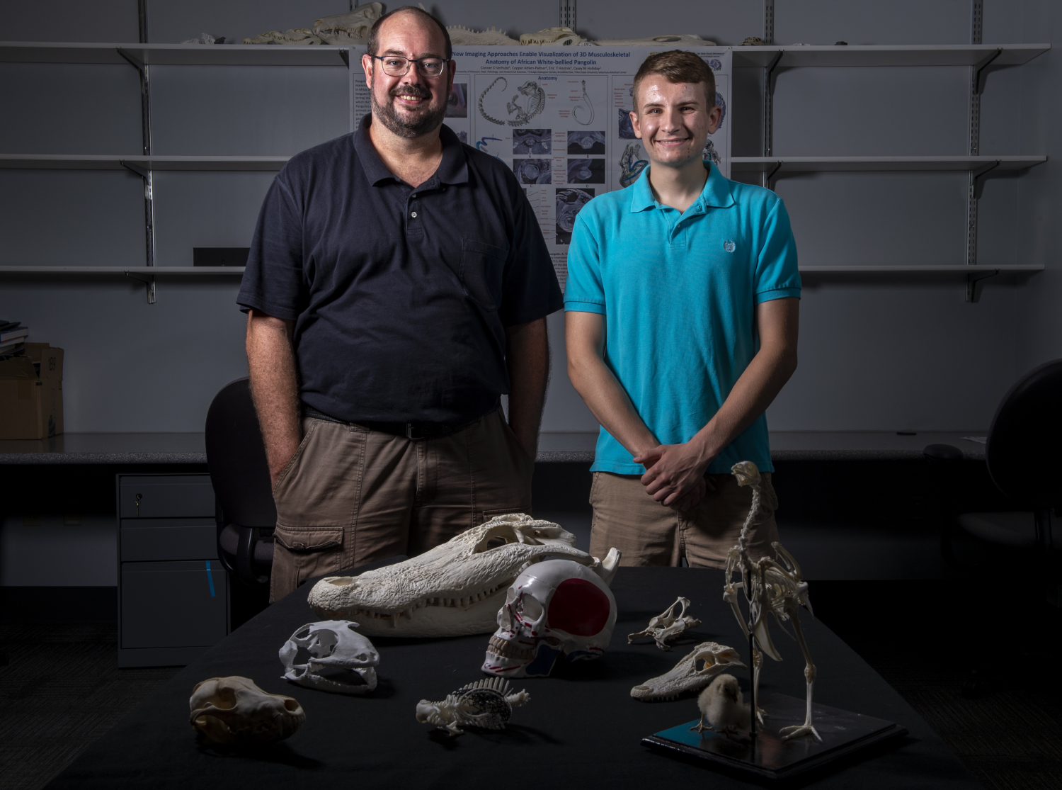 Casey Holliday and Conner Verhulst stand behind a display table of animal skulls.