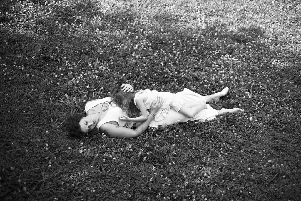 Mother and daughter lay on grass